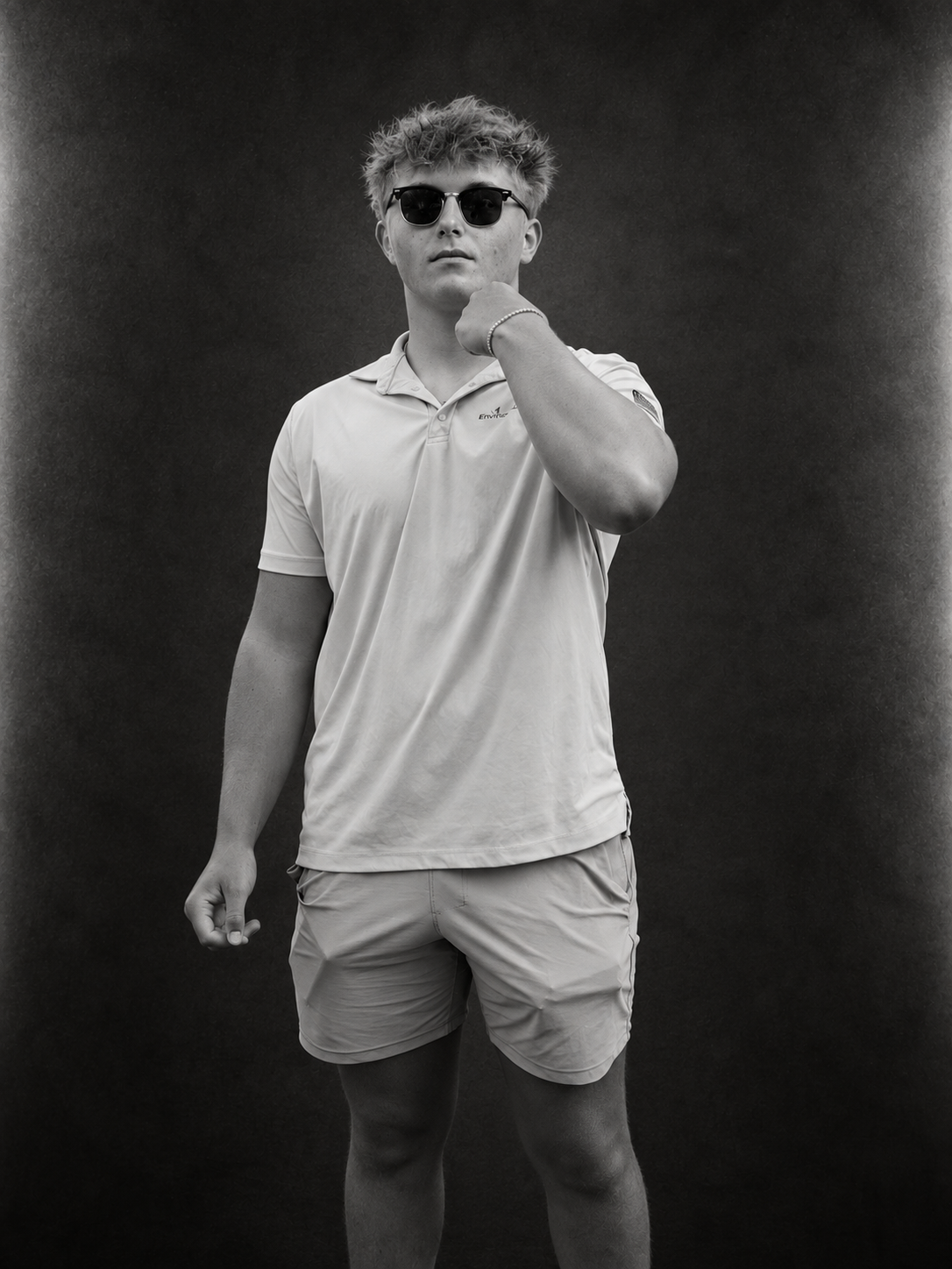 Jaxon James in a light polo and round sunglasses